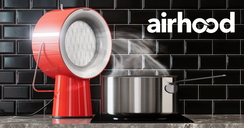 AirHood ad image: the red AirHood on a marble counter against black subway tile, drawing steam off a steel stockpot on an induction hob, beside a large white airhood wordmark
