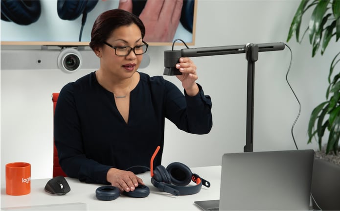 A professional angles the Reach camera at headphones on her desk during a video call.