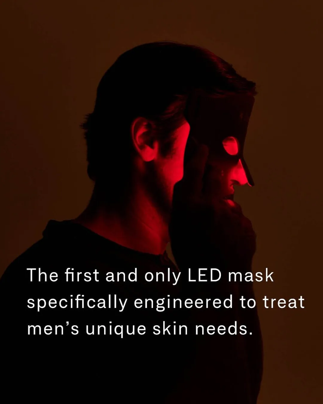 Omnilux Men ad image: a man in near-darkness holds the LED mask to his face, his profile lit red through its eye and mouth openings, over the line “The first and only LED mask specifically engineered to treat men’s unique skin needs.”