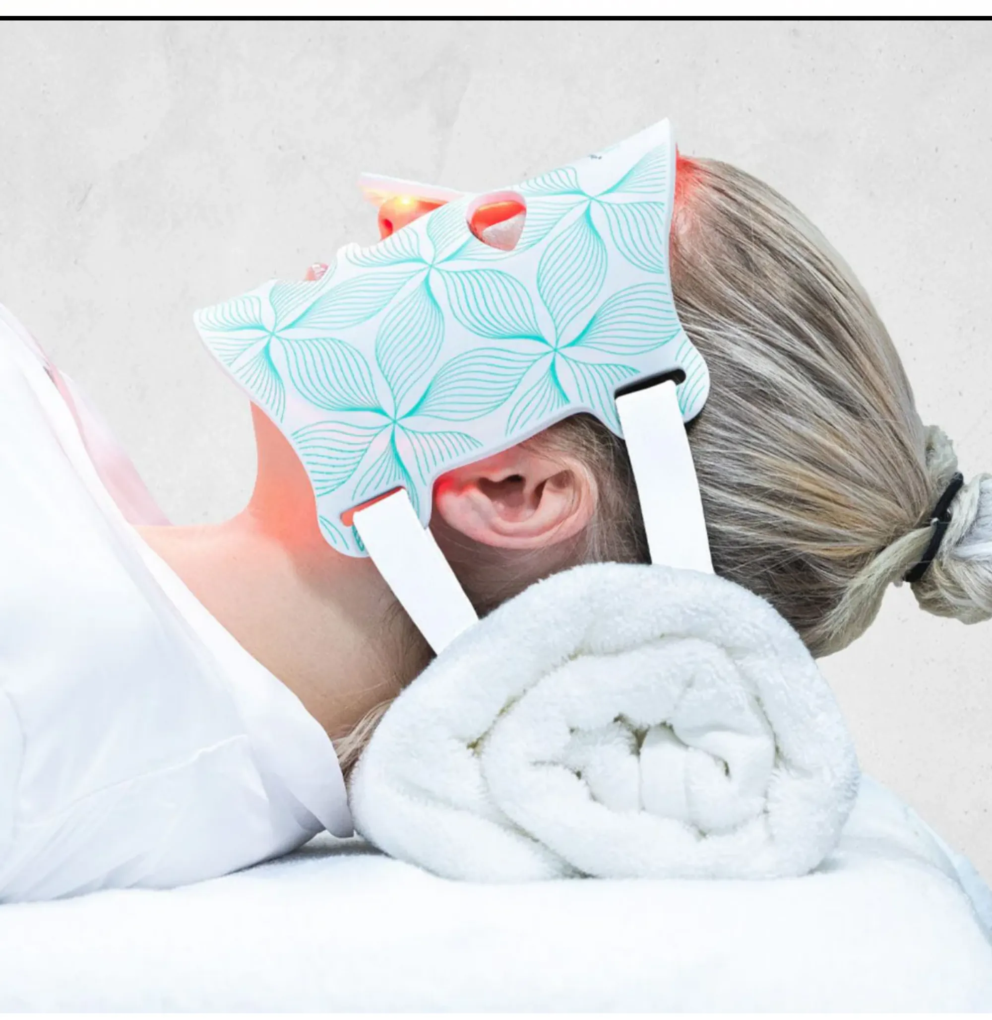Woman lying down wearing an Omnilux LED light therapy mask.