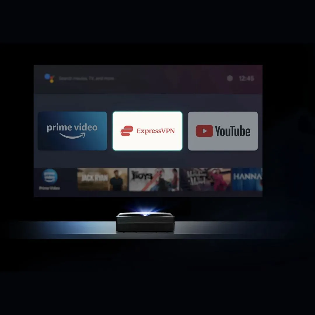 A Screeneo U5 on a shelf projects a streaming home screen with Prime Video, ExpressVPN and YouTube tiles, ExpressVPN highlighted